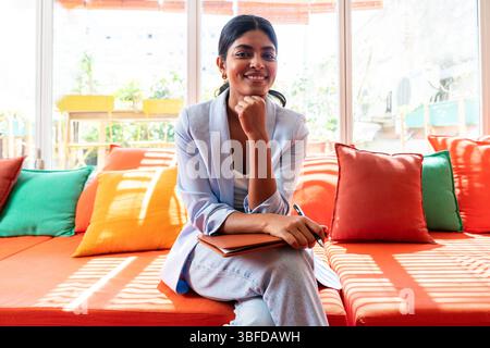 Beautiful indian business woman working in a coworking corporate company office - Young female wearing business casual clothing works in a creative st Stock Photo