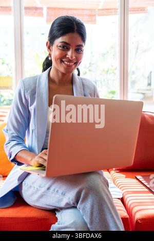 Beautiful indian business woman working in a coworking corporate company office - Young female wearing business casual clothing works in a creative st Stock Photo