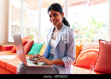 Beautiful indian business woman working in a coworking corporate company office - Young female wearing business casual clothing works in a creative st Stock Photo