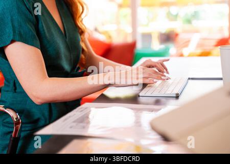 Beautiful caucasian business woman working in a coworking company office at computer desk - Young female wearing business casual clothing works in a c Stock Photo