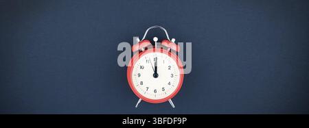 Concept image of a red vintage alarm clock with twelve o clock on dark blue color paper background with copy space in minimal style, template for text Stock Photo