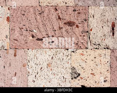 surface of wall tiled with pink armenian tuff stone lit by morning sun in Kapan town, in Syunik Province of Armenia Stock Photo