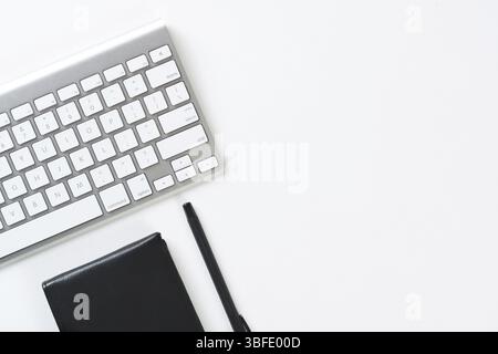Still life of modern office workspace with supplies. Flat lay white desk with black leather wallet and computer keyboard. Online shopping and payment. Stock Photo