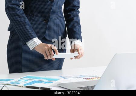 Businesswoman doing photo of paper document with smartphone. Online stock trading and investment. Manager in suit working with business analytics. Dig Stock Photo