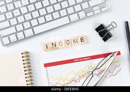 Money income concept with letters on wooden cubes. Still life of office workplace with supplies. Flat lay white surface with computer keyboard and ana Stock Photo