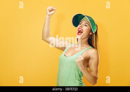 Excited young woman celebrating success with her fists clenched. for concepts like sports, fitness, lifestyle, and personal achievement. Stock Photo