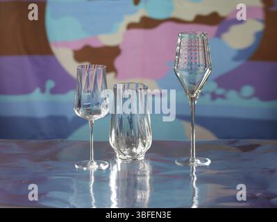 Various glasses on silver foil, behind them various colour elements, studio shot Stock Photo