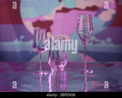 Various glasses on silver foil, behind them various colour elements, studio shot Stock Photo