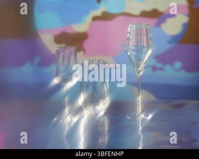 Various glasses on silver foil, behind them various colour elements, studio shot Stock Photo