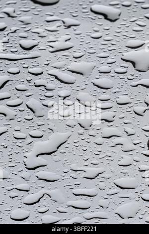 Rain drops on glass create a serene and reflective atmosphere during a gray and rainy day Rain drops accumulate on a glass surface, transforming it in Stock Photo