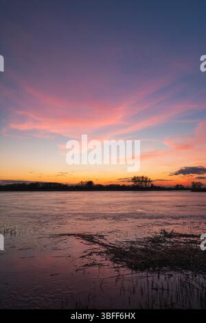 Evening colorful clouds on the blue sky over the frozen lake Stock Photo