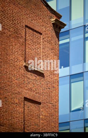 Manchester old and new, the red brick building contrasts with the new glass clad building Stock Photo
