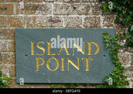 Green Stone Plaque with Golden Letters Set Against a Brick Wall. Hayling Island, UK Stock Photo
