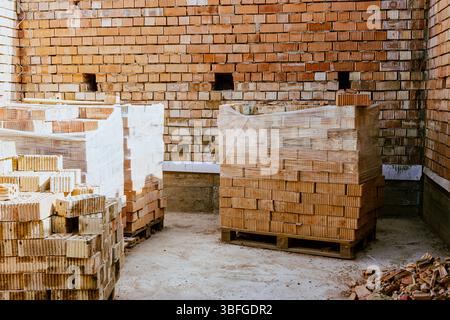 Building materials are on floor, stack red bricks. Production high-quality ceramic brick matte, reddish, porous fracture. Brick used for laying foundation. Purchase building material at hardware store. High quality photo Stock Photo