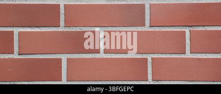 Full-frame close-up modern red brick wall background with a uniform horizontal tile pattern. Red Clay bricks and precise grout lines. Construction. Stock Photo