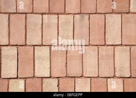Close-up full-frame classic red brick wall, fired clay bricks arranged in a uniform horizontal pattern. Textured surface and rustic tone. Masonry. Stock Photo