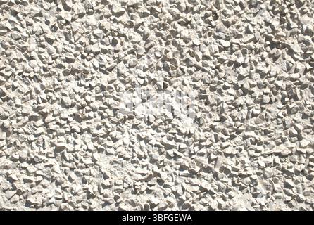 Close-up full-frame roughcast or pebble dash wall with a coarse, textured surface created by embedded small stones. Rugged, light gray urban exterior. Stock Photo