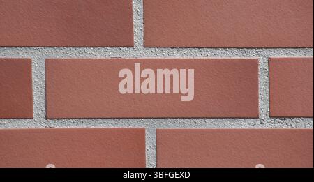 Full-frame close-up modern red brick wall background with a uniform horizontal tile pattern. Red Clay bricks and precise grout lines. Construction. Stock Photo