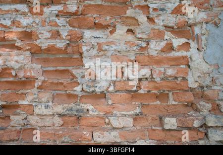 Close-up full-frame old brick wall with red and white weathered bricks and exposed mortar. Rustic, chipped surface, age and decay. Textured background Stock Photo