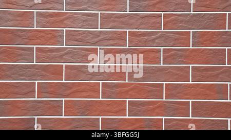 Full-frame close-up image, red brick tile wall with clean grout lines and a uniform pattern. Modern masonry texture, smooth ceramic surfaces. Stock Photo