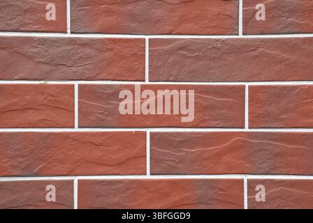 Full-frame close-up image, red brick tile wall with clean grout lines and a uniform pattern. Modern masonry texture, smooth ceramic surfaces. Stock Photo