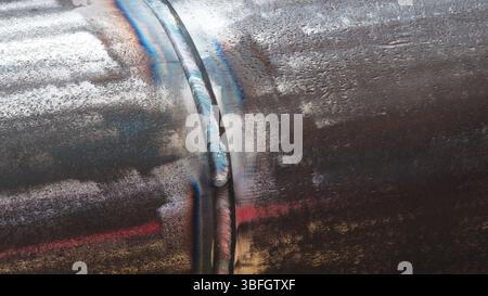 A rusty pipe with a welded joint. The joint is visible and the pipe is covered in rust industrial concept background. Stock Photo
