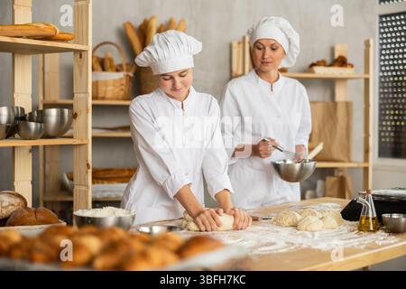 Female bakers in uniform preparing gray dough Stock Photo