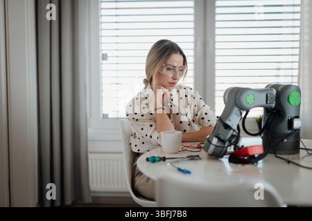 Woman engineer working on robotic arm project at home. Stock Photo