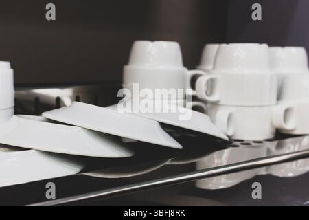 Kitchen utensil. White cutlery. Clean plates and cups on metal table. Kitchenware isolated. White dishes and mugs. Restaurant porcelain cutlery. Stock Photo