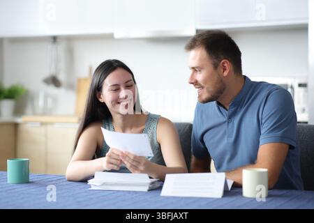 Happy interracial couple talking about letter in the kitchen at home Stock Photo