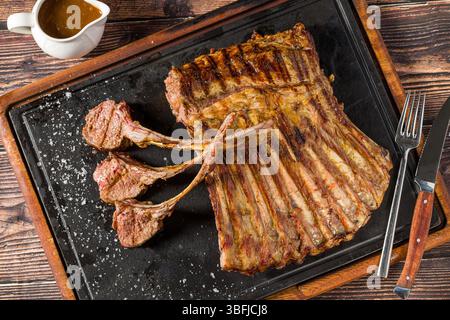 Lamb racks grilled with herbs and sauce on a stone board Stock Photo