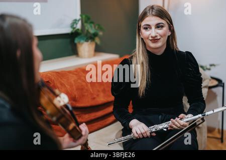 Two young musicians practicing violin and flute together in a cozy room Stock Photo