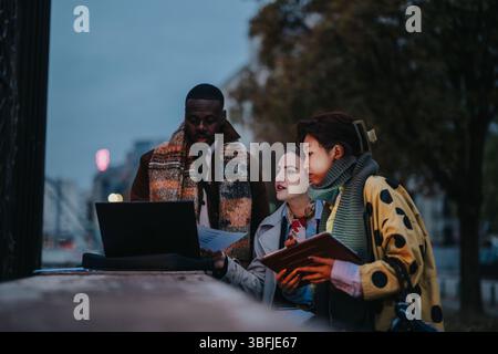 Multiracial business team collaborating outdoors with a laptop Stock Photo