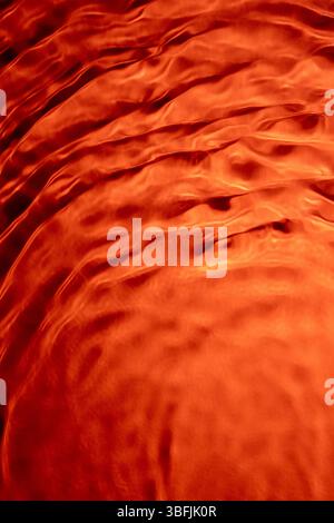 Flowing orange water creating a smooth and textured surface Stock Photo