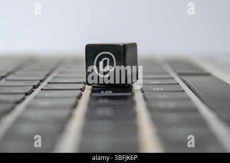 A cube with an at sign or at symbol on a laptop keyboard. Email, internet, communication concept. Stock Photo