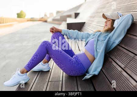Young woman relaxing with headphones on urban bench Stock Photo