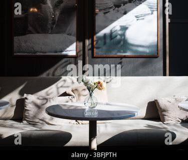 flowers on a table in a cafe with sun shining through the window Stock Photo