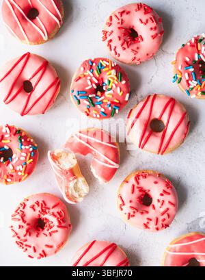 Top view of donuts with pink glaze and sprinkles on gray background. Stock Photo