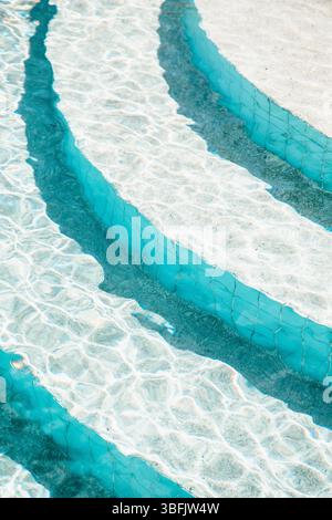 Sunlit turquoise pool steps with rippling water reflections Stock Photo
