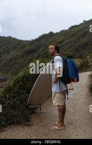 Young man carrying surfboard and walking to beach Stock Photo