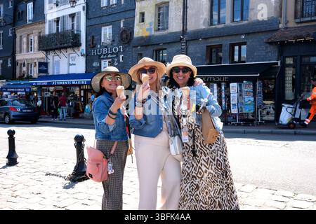 Foreign tourists taking a fun selfie photograph at Honfleur in France. Stock Photo