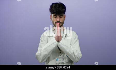 Young man in lab coat gesturing on purple background with focus on expression and attire. Stock Photo