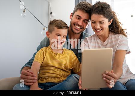 Happy family, parents with cute excited small kids son using laptop computer at home. Technology Stock Photo