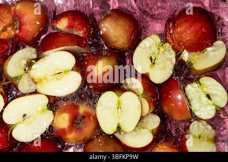 Juicy Whole and Cut Red Apples Close-Up in Water Splash Top View. Stock Photo