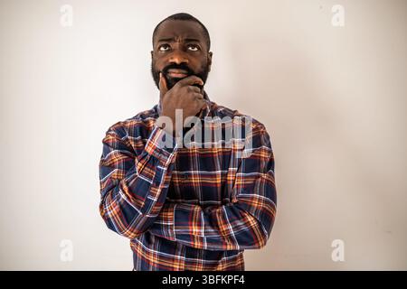 Pensive black man in cozy shirt shirt lying on wall, looking up and thinking. Stock Photo