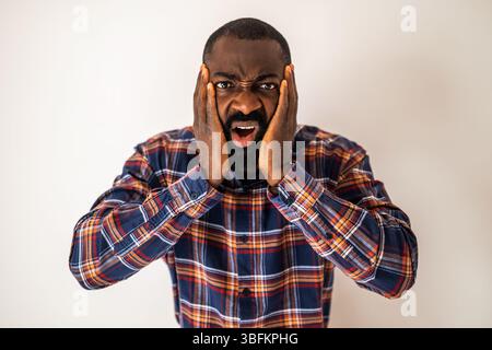 Portrait of emotionally stressed, confused and shocked black man who is looking at camera. Stock Photo