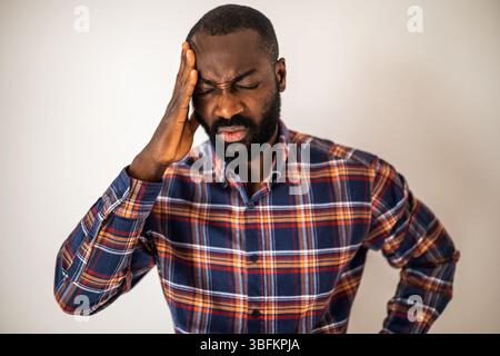 Portrait of black man who is anxious and having headache. Adult man is tired and overworked. Stock Photo