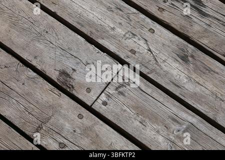 Close-up of diagonal wooden planks with visible grain and nails. Weathered surface texture ideal as rustic background or design element. Stock Photo