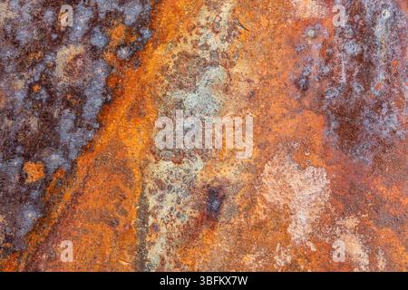 Front view of a heavily rusted iron plate with bright orange rust spots, used as a background or texture. Stock Photo
