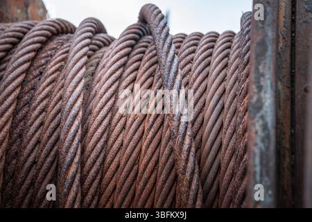 Rusty steel cable coil on old industrial winch from abandoned shipyard, close-up detail view Stock Photo